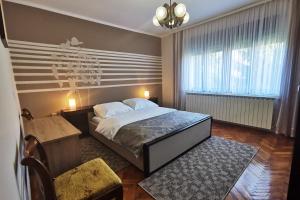 a bedroom with a bed and a table and a chair at Apartman Škudar in Bjelovar