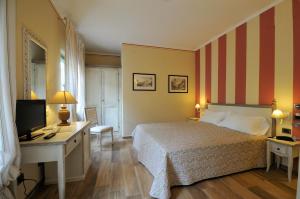 una camera con letto e scrivania con TV di Hotel Dei Conti a Castelnuovo di Val di Cecina