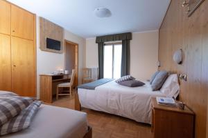a hotel room with a bed, desk and a television at Hotel Cima Piazzi in Valdidentro