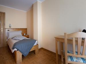 niewielka sypialnia z łóżkiem i drewnianym stołem w obiekcie Hotel Cima Piazzi w mieście Valdidentro