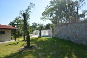a yard with a stone wall and a tree at Quinta da Cachada in Moure