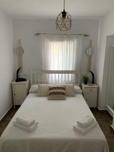 1 dormitorio con 1 cama blanca grande y 2 toallas en Panorama Village, en Barbate