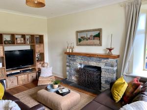 a living room with a fireplace and a tv at Blair Cottage in Rowardennan