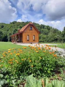 a wooden house with a field of flowers in front of it at Spirit of Velebit in Gospić