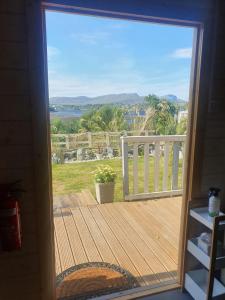 a door to a deck with a view of the ocean at An Traigh Cabin in Portree