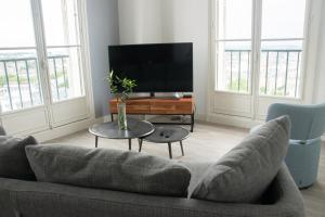 ein Wohnzimmer mit einem Sofa und einem TV in der Unterkunft 15ème droite - Tour Perret - Centre-Ville - 4 étoiles in Amiens