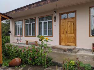 una casa con una puerta de madera y algunas flores en Tatev Guest House en Tatʼev