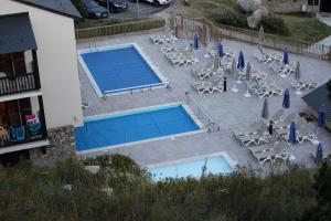 una vista panoramica su due piscine con sedie e ombrelloni di Résidence Mille Soleils - Font Romeu a Font-Romeu-Odeillo-Via