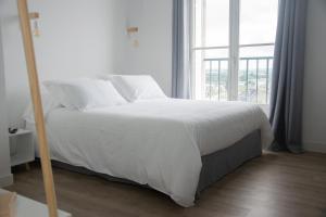een wit bed in een kamer met een groot raam bij 15ème droite - Tour Perret - Centre-Ville - 4 étoiles in Amiens