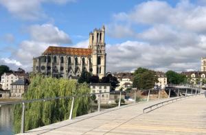 un ponte su un fiume con un edificio sullo sfondo di Appartement avec Jardin et Terrasse près de Paris a Mantes-la-Jolie