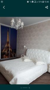 um quarto com uma cama branca e uma torre Eiffel. em Альтаир2 em Odessa