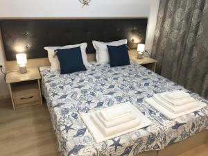 a bedroom with a bed with blue and white sheets and pillows at Студио Сънрайз А28, Лозенец in Lozenets +32 photos