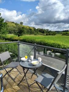 una mesa y sillas en un balcón con vistas en Gerycastell Luxury Holiday Apartment with Stunning Views & EV Station Point, en Carmarthen