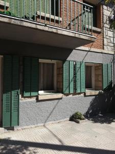 un edificio con ventanas con persianas verdes y balcón en LA CASA DE LOS ABUELOS en Las Navas del Marqués