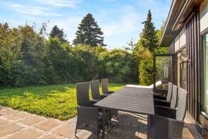 Une table et des chaises en bois sont disponibles sur la terrasse. dans l'établissement Cozy summer house 50 meter from the beach, 89 m², à Dronningmølle