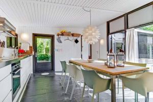 Cozy summer house 50 meter from the beach, 89 m² في Dronningmølle: مطبخ مع طاولة وكراسي خشبية