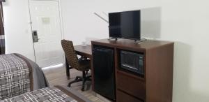 a room with a desk with a television on a cabinet at Key West Inn - Boaz in Boaz