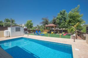 una piscina con un parque infantil en el fondo en Ariella Villa en Protaras