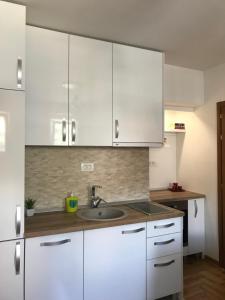 a kitchen with white cabinets and a sink at Apartman Tijana in Budva