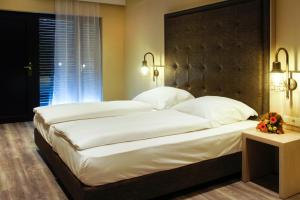 ein Schlafzimmer mit einem großen Bett mit weißen Laken und Kissen in der Unterkunft Hotel Athen Kelsterbach Frankfurt Airport in Kelsterbach + 30 Fotos