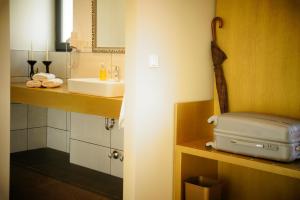 a bathroom with a sink and a suitcase on a shelf at Hotel Athen Kelsterbach Frankfurt Airport in Kelsterbach