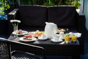 Hotel Athen Kelsterbach Frankfurt Airport في كلسترباخ: طاولة إفطار مع مجموعة شاي على كرسي الخوص