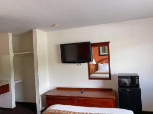 um quarto de hotel com uma televisão de ecrã plano na parede em Royal Inn Richmond Hill- Savannah I-95 em Richmond Hill