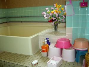 a bathroom with a tub and a vase of flowers at Minshuku Mutsukari in Furano