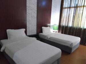 a hotel room with two beds and a window at Ginasuite Kompleks27 Hotel in Bandar Seri Begawan