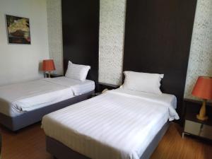 duas camas num quarto de hotel com lençóis brancos em Ginasuite Kompleks27 Hotel em Bandar Seri Begawan