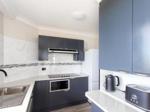 a kitchen with gray cabinets and a sink at Heritage 202 in Tuncurry