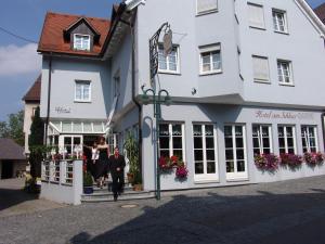 Ein Paar geht aus einem weißen Gebäude in der Unterkunft Hotel am Schloss Neuenstein in Neuenstein