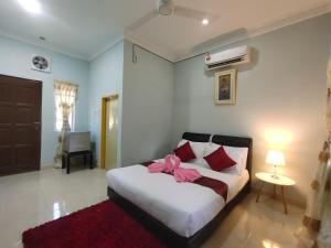 a bedroom with a bed with a pink bow on it at Ku's Roomstay in Pantai Cenang