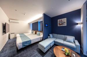 ein Hotelzimmer mit einem Bett und einem Sofa in der Unterkunft GRAND BASE Okayama Ekimae in Okayama