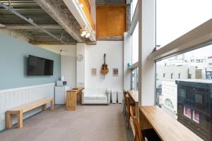 a room with a large window and a tv and benches at bnb+ Yokohama Motomachi in Yokohama