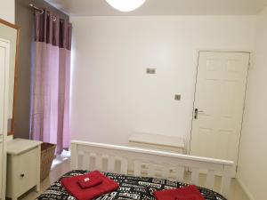 a bedroom with a bed with two red towels on it at Taj Suite in Ipswich