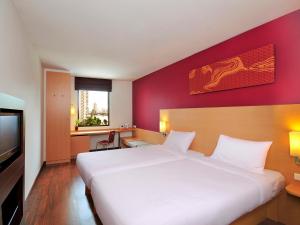 a bedroom with a white bed and a red wall at Ibis Bangkok Riverside in Bangkok
