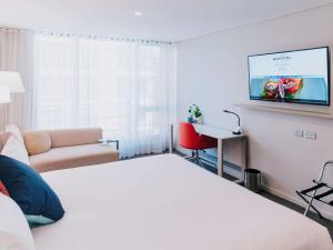 a hotel room with a bed and a flat screen tv at Novotel Newcastle Beach in Newcastle