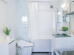 Un baño blanco con inodoro y ducha. en Urbanage Takadanobaba apartment, en Tokio