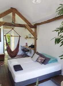a bedroom with a bed in a room with a hammock at La petite maison du jardin d'Apollon in Dourdan