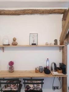 uma prateleira de madeira numa parede com duas cadeiras em La petite maison du jardin d'Apollon em Dourdan