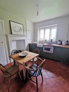 a kitchen with a wooden table and chairs and a sink at The Coach House in Cholderton