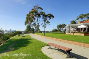 a park bench on a sidewalk next to a building at Swan River Applecross Heathcote Park 1BR Villa in Perth