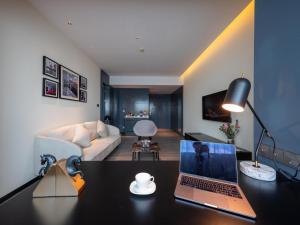 a room with a desk with a laptop and a couch at Paradigm Style Hotel(Guangzhou Taiguhui) in Guangzhou