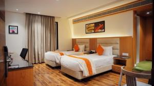 a hotel room with two beds and a television at Kyriad Hotel Gulbarga by OTHPL in Gulbarga