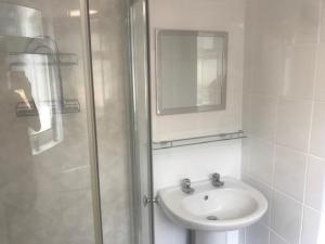 a white bathroom with a sink and a shower at Gwynedd House Flat 3 in Pentraeth