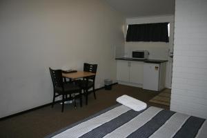 1 dormitorio con 1 cama, mesa y sillas en The Plains Motor Inn, en Gunnedah