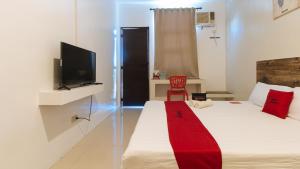 a bedroom with a bed and a tv and a red blanket at RedDoorz @ Golite Washington in Legazpi