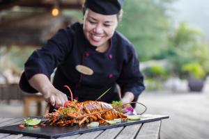 un chef que prepara un plato de comida en una mesa en L'Alya Ninh Van Bay en Ninh Van Bay