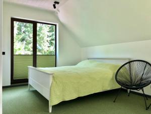 a white bedroom with a bed and a chair at Holstre Paradiis in Holstre